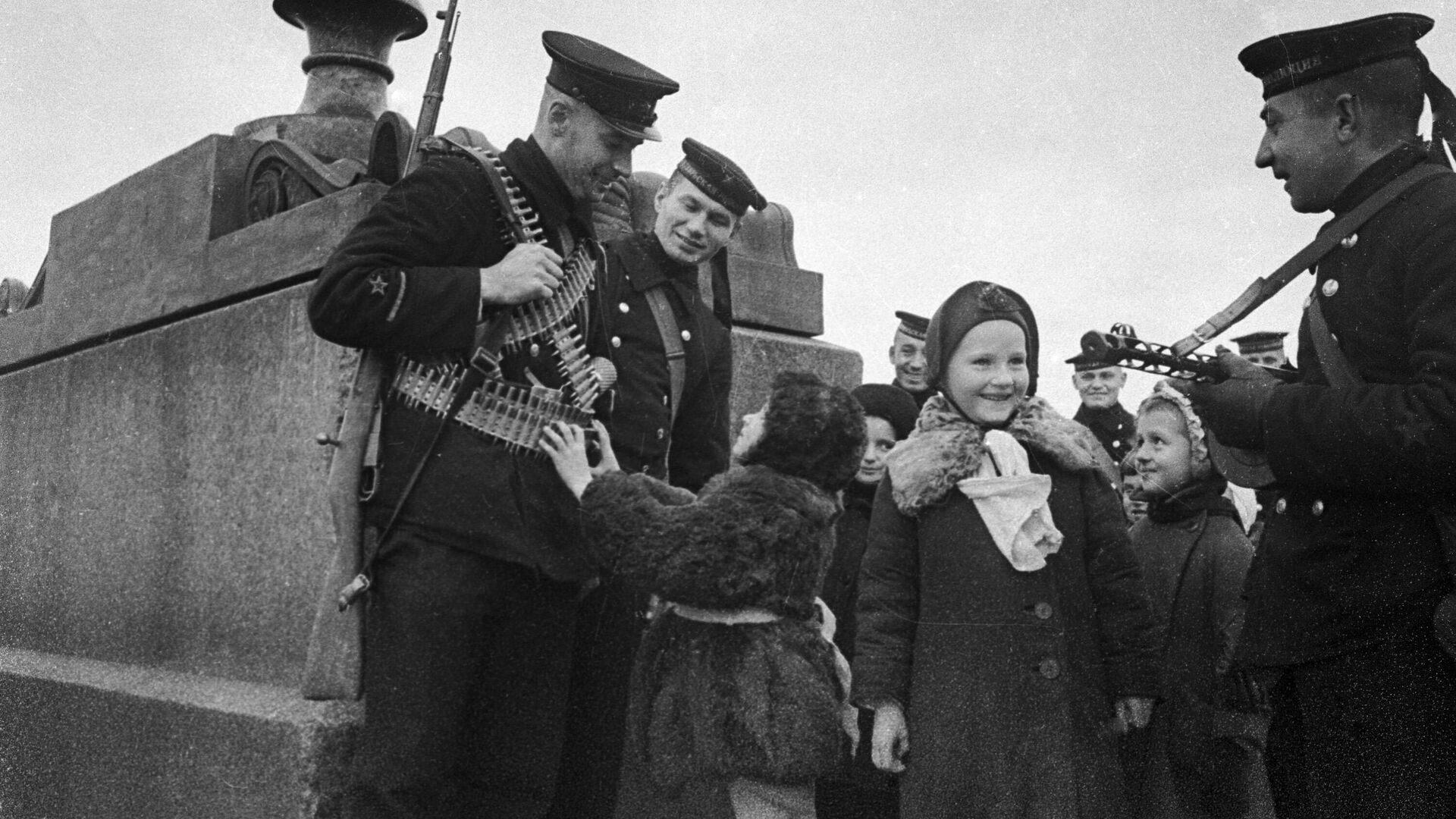 Защитники блокадного Ленинграда. Советские моряки общаются с детьми на набережной реки Невы. © РИА Новости / А. Бродский